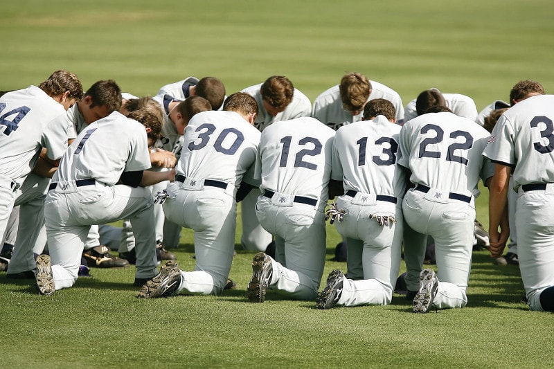 A baseball team kneeling to pray before a game